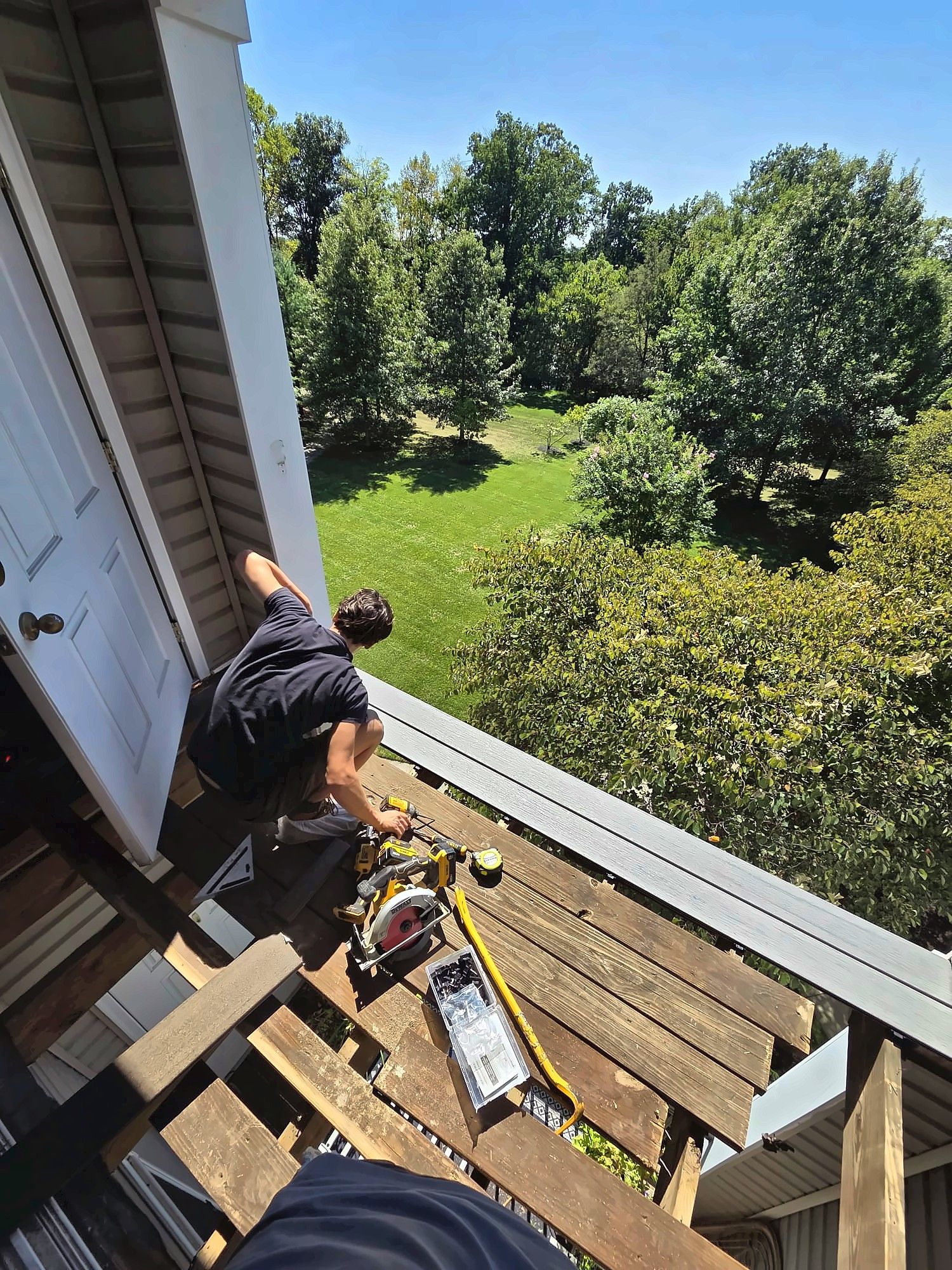 Crew member cutting new boards on a high balcony deck