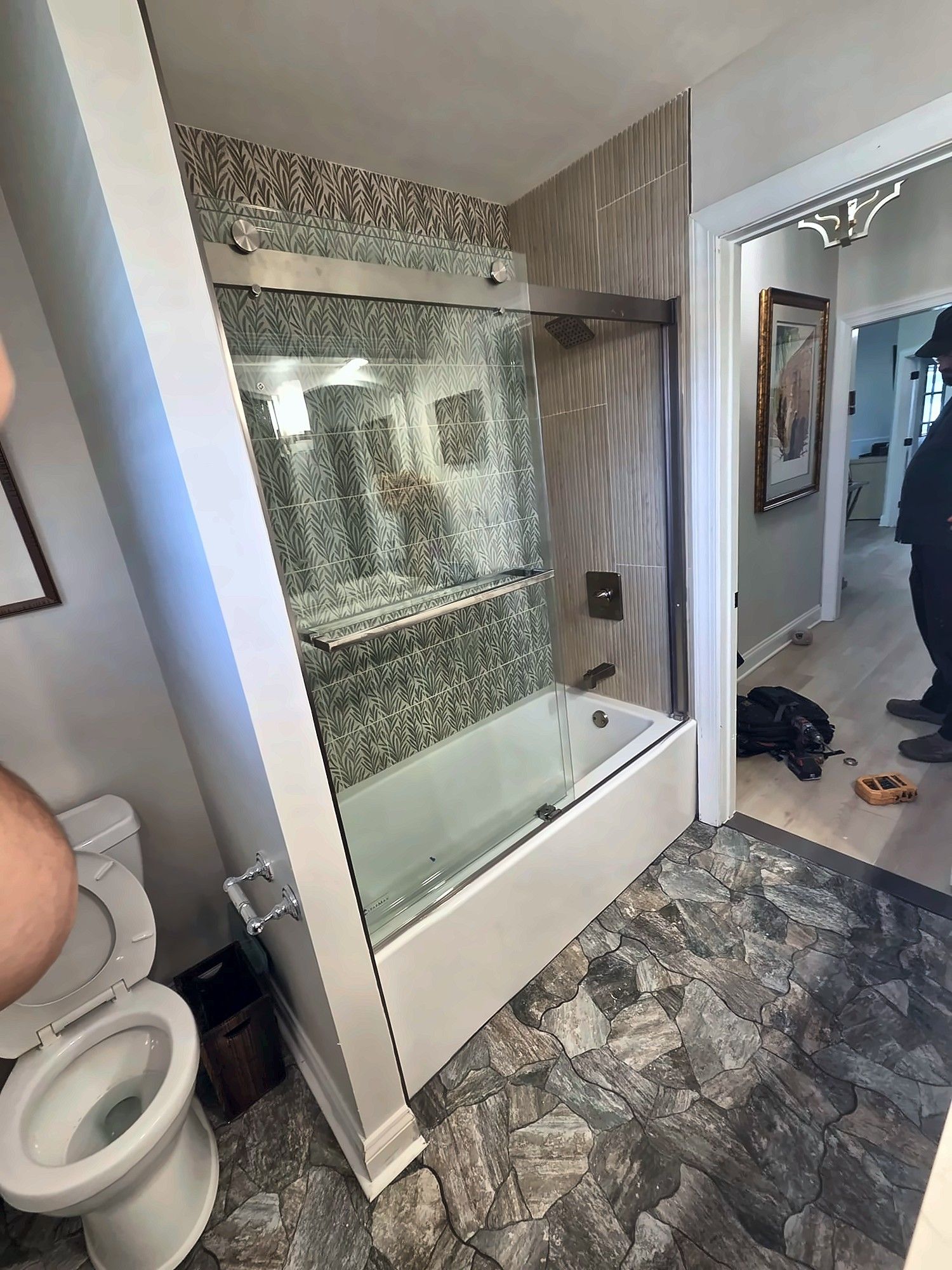 Finished bathroom with glass tub doors seen from the hallway
