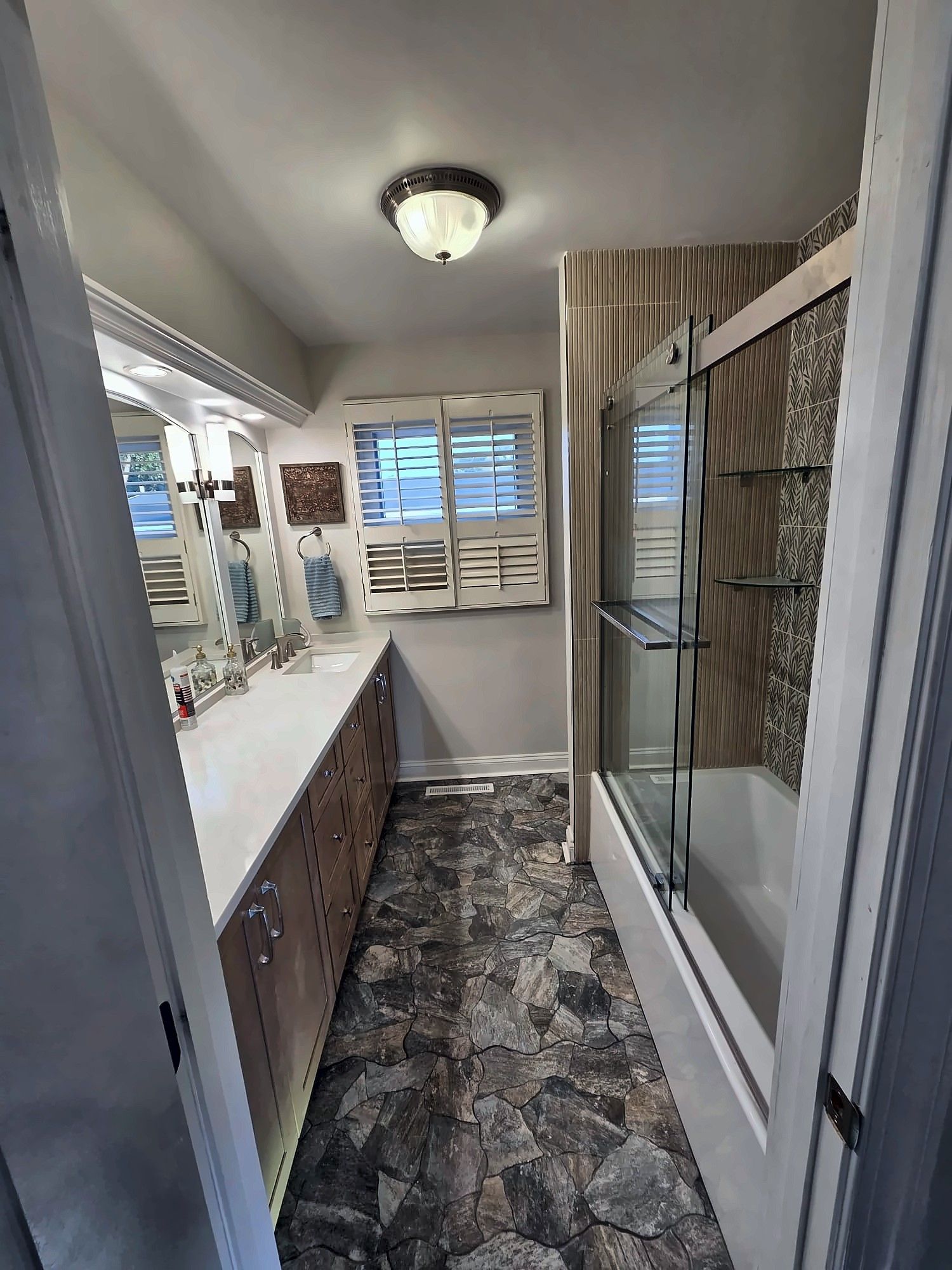 Wide view of a remodeled bathroom with stone-look floor