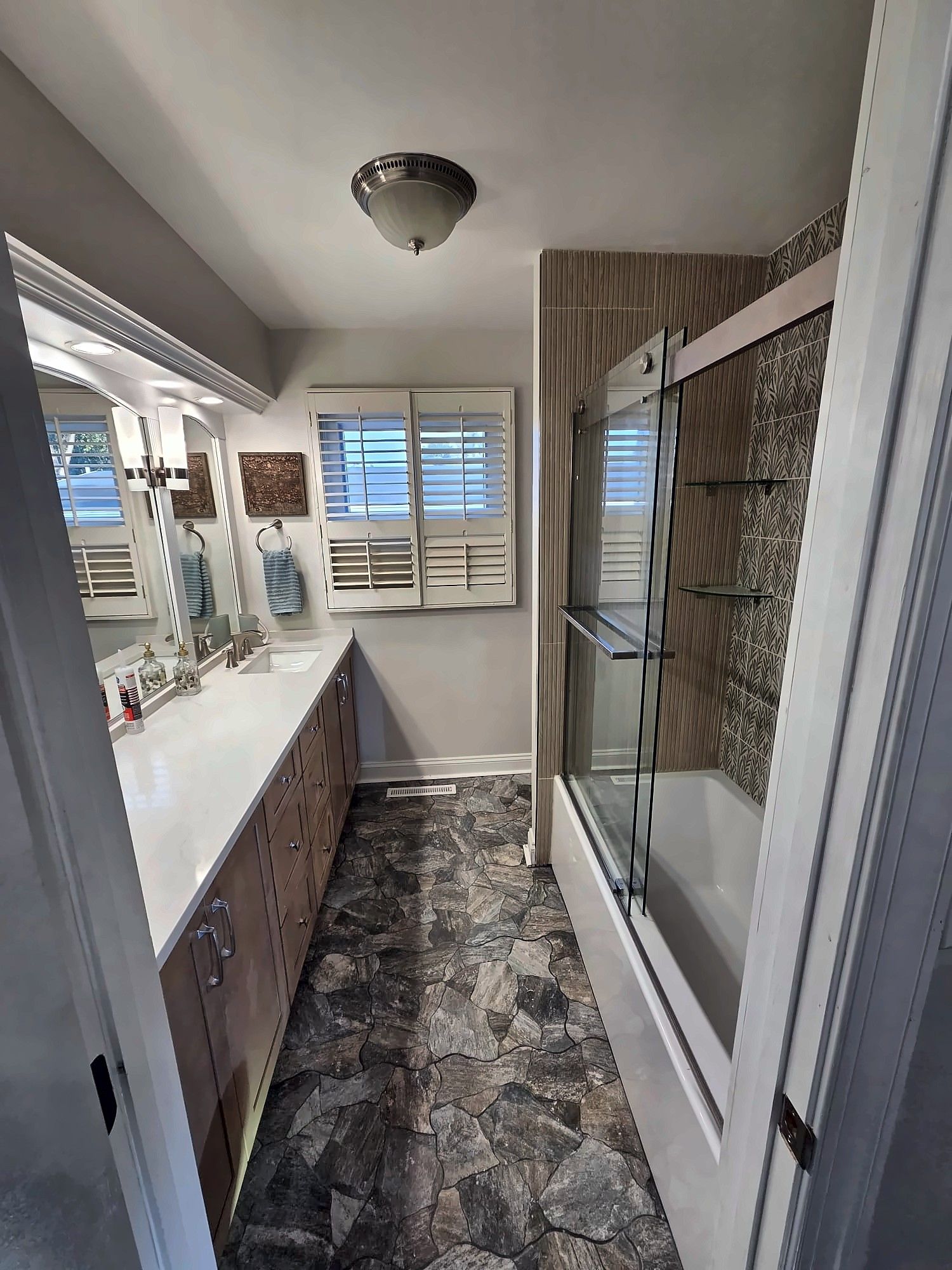 Remodeled bathroom with long vanity and sliding glass tub doors