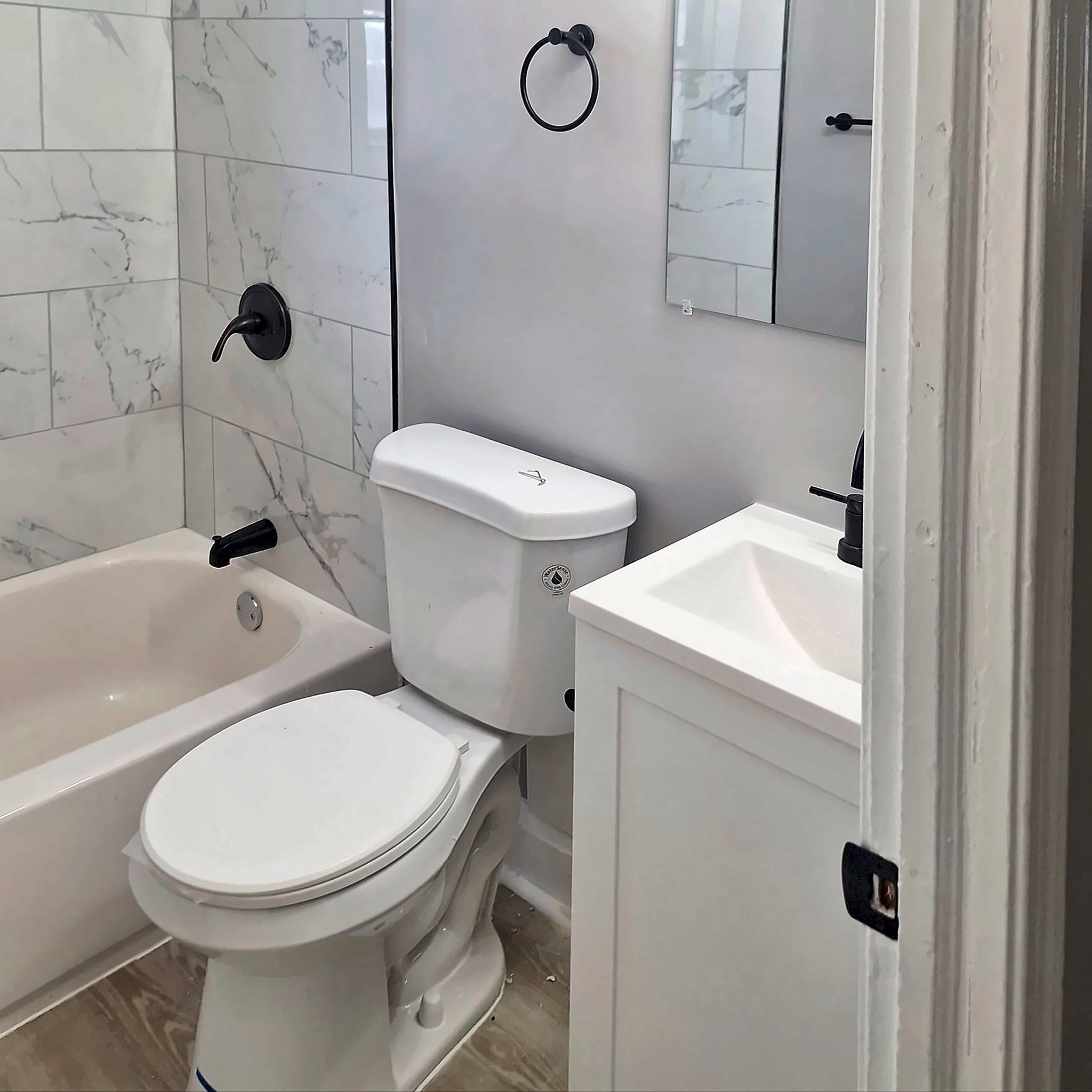 Remodeled bathroom with marble-look tile tub surround and matte black fixtures