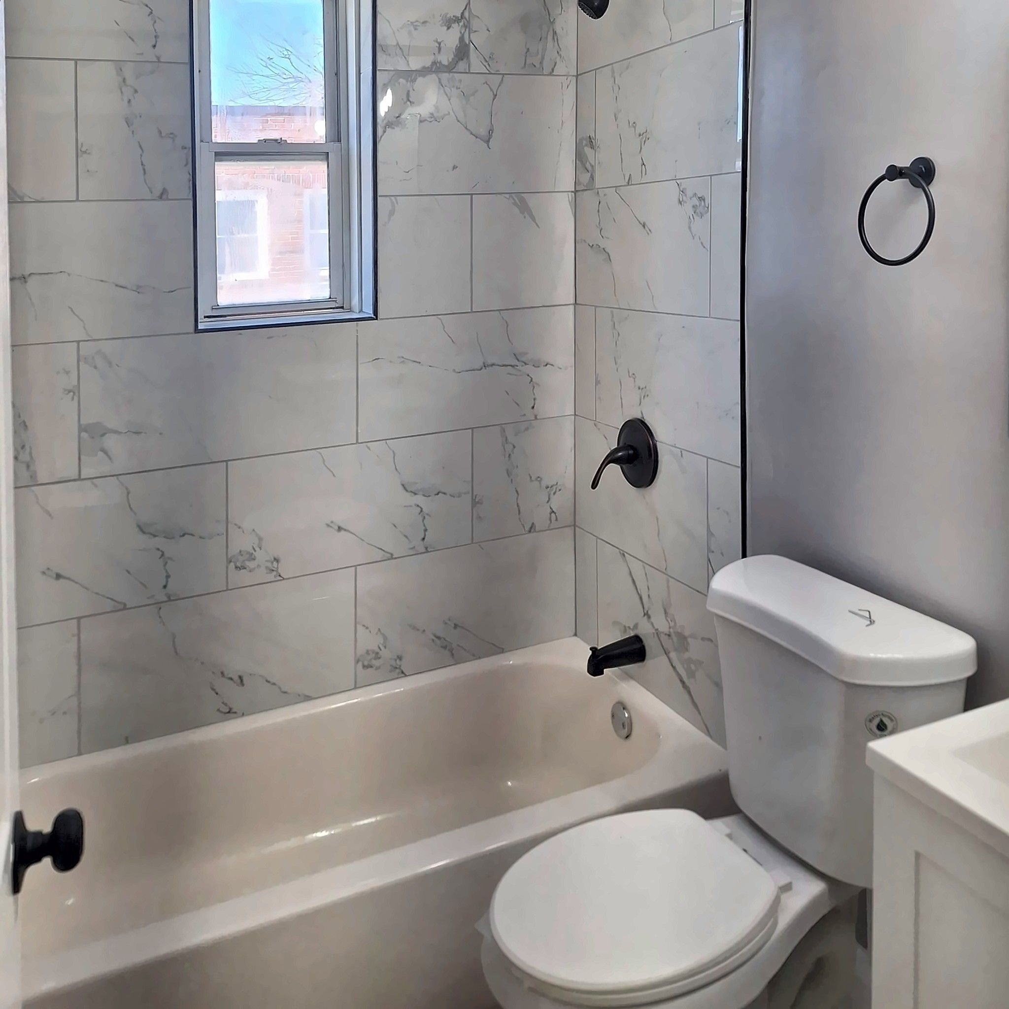 Tiled tub surround with window and matte black shower fixtures