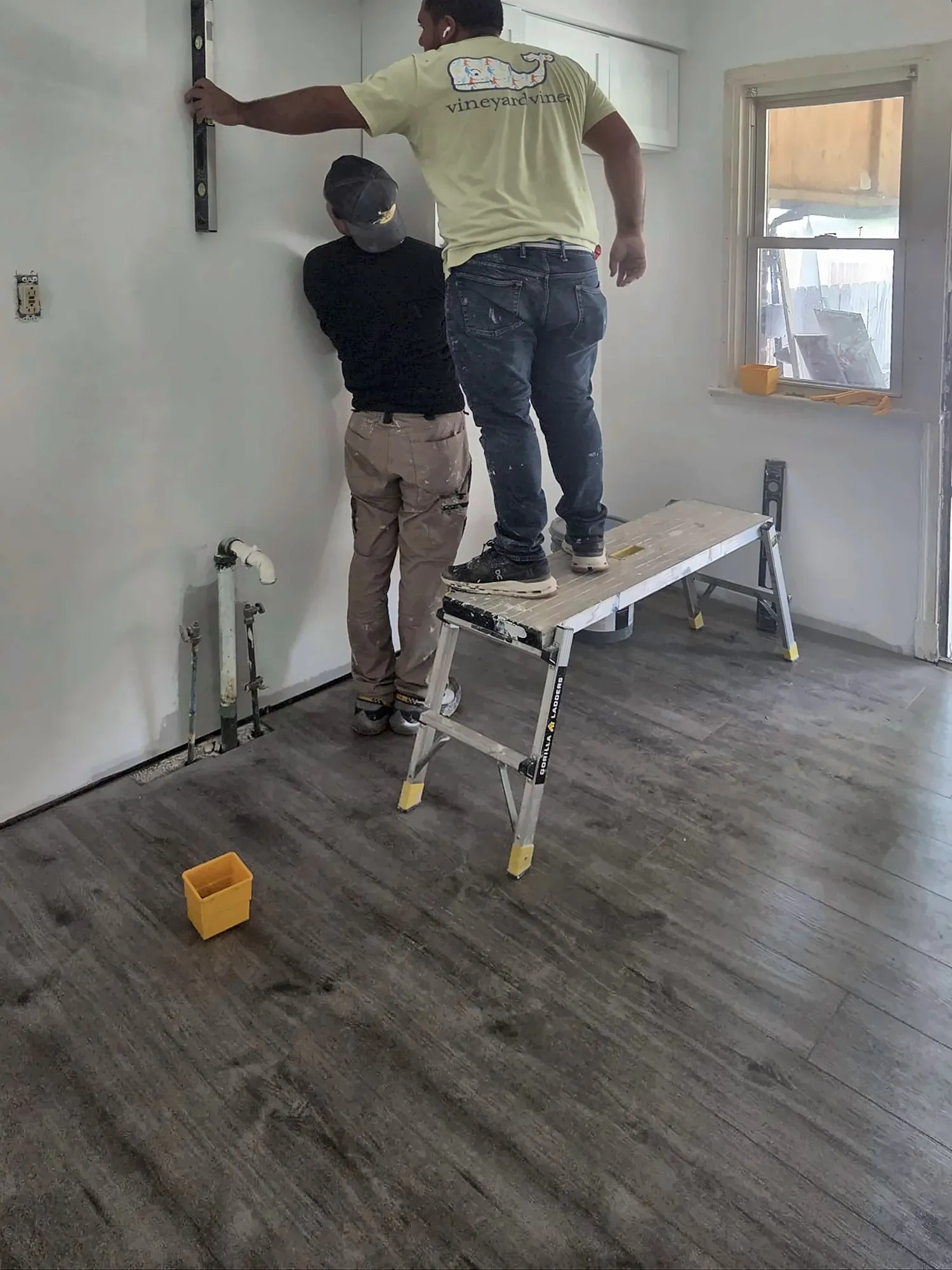 Crew leveling a wall for kitchen cabinet installation