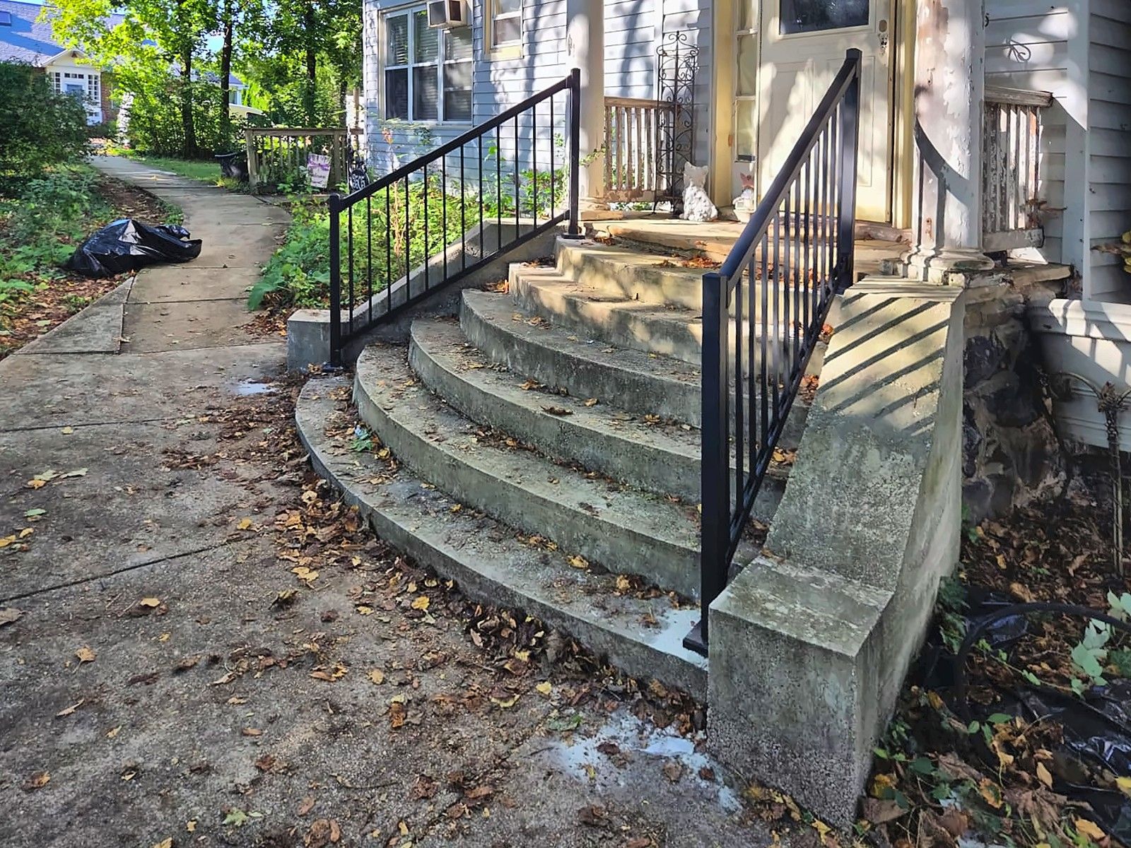 Curved concrete front steps with black metal handrails