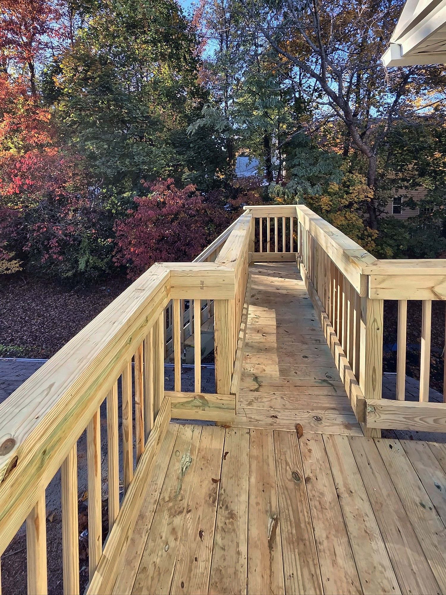 Wood deck walkway with railings and autumn trees