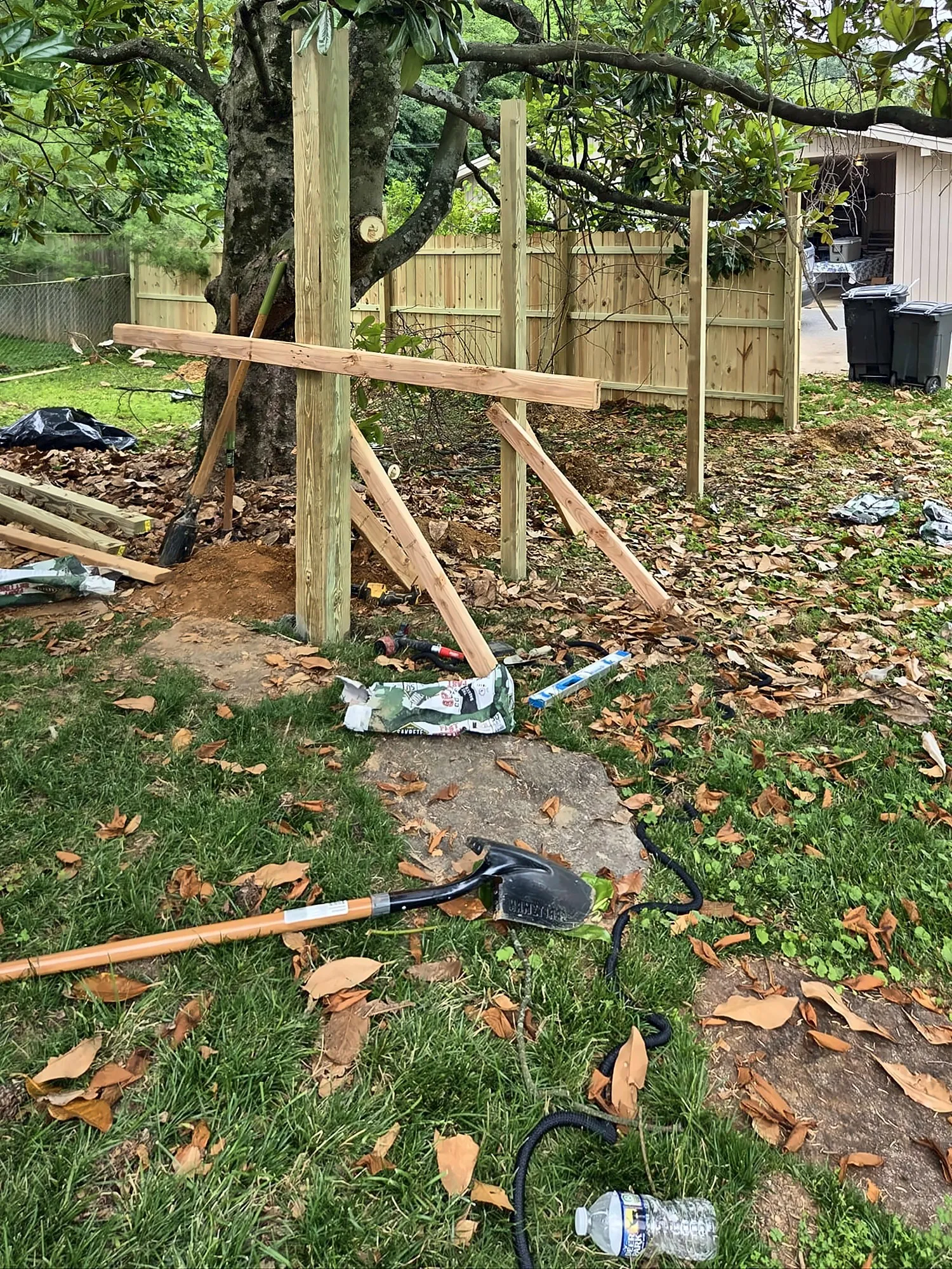 Fence posts being installed and braced in a backyard
