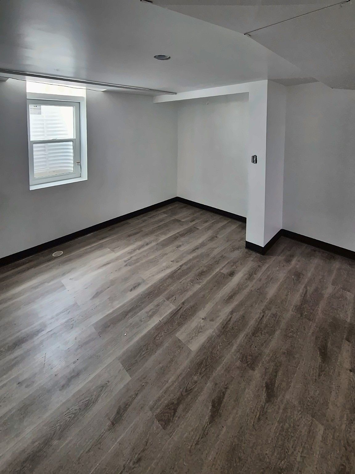 Finished basement room with gray vinyl plank flooring