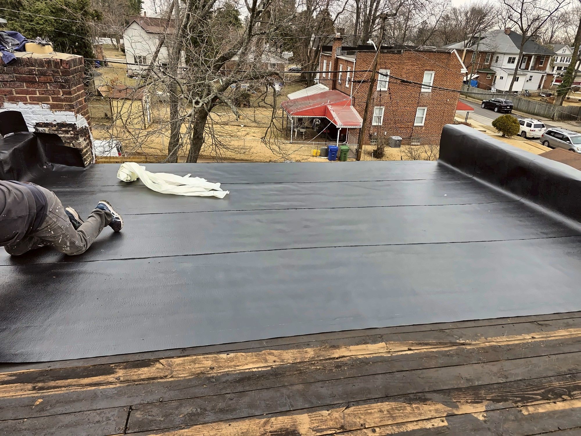 Roofer installing new flat roof membrane on a rowhouse