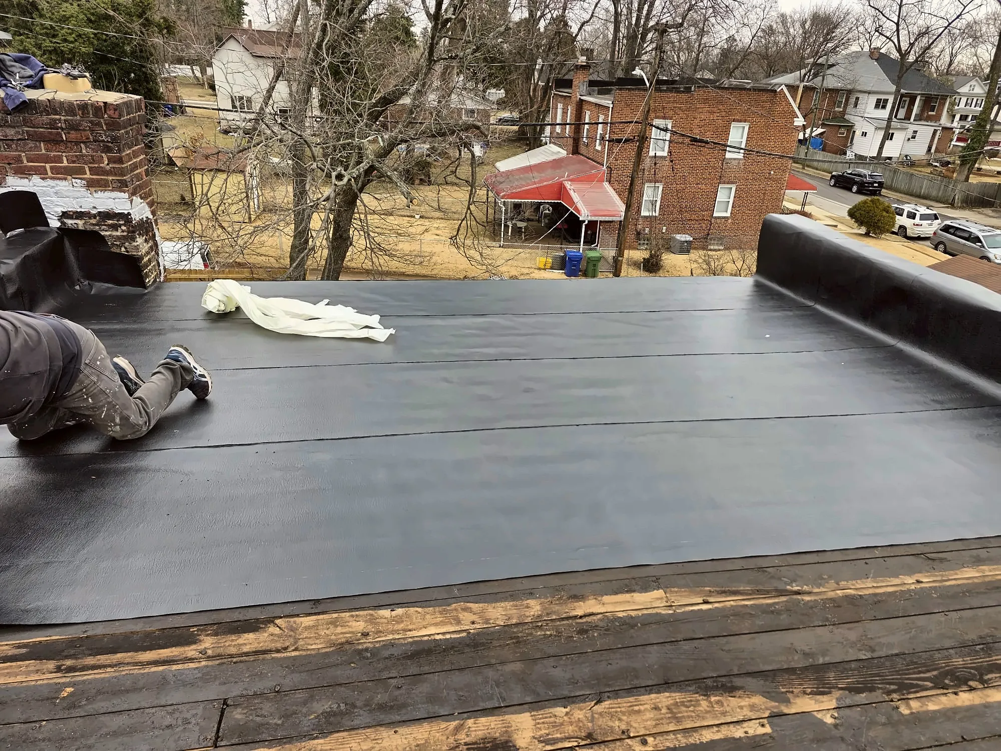 Roofer installing new flat roof membrane on a rowhouse