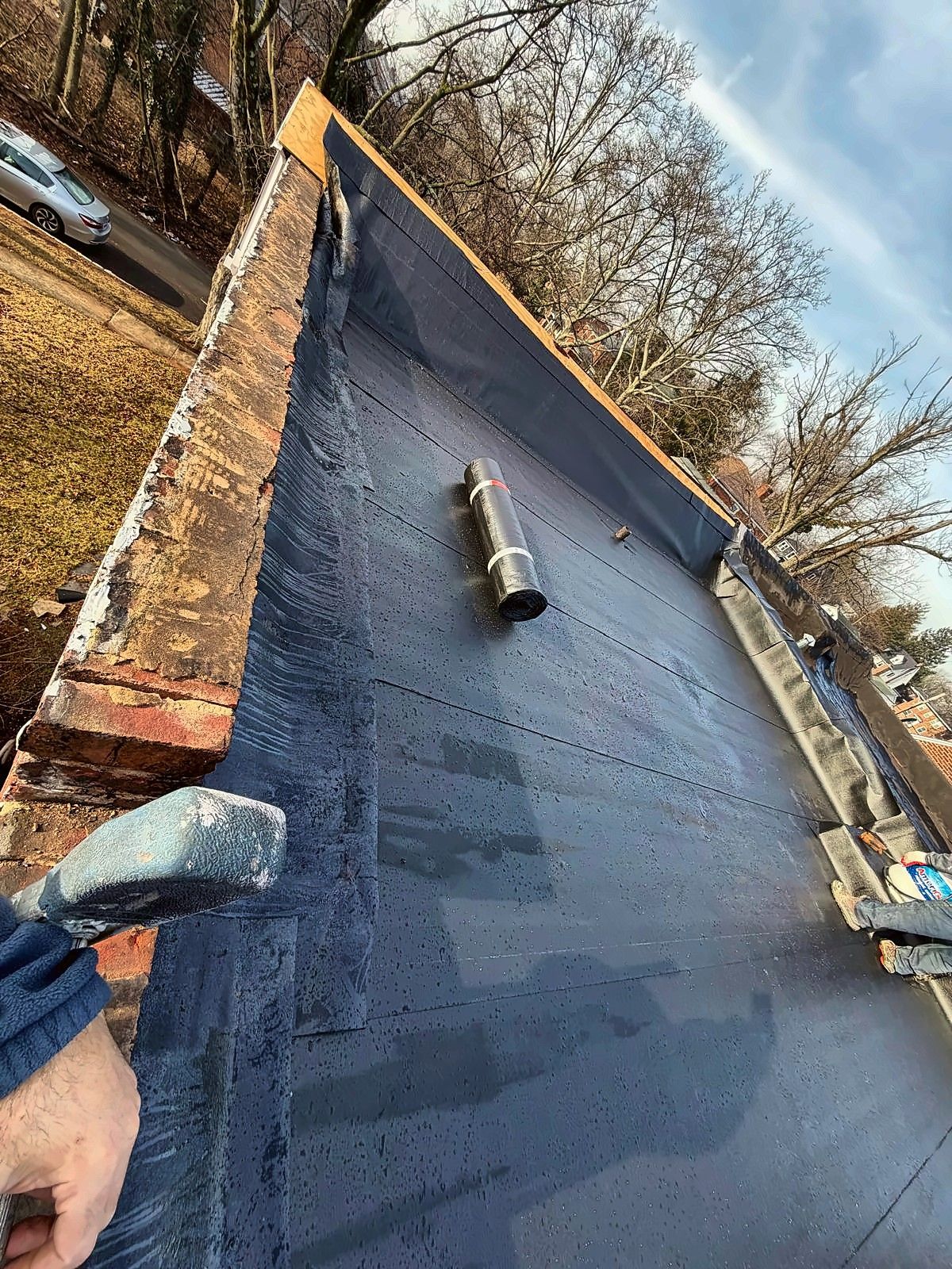 New flat roof membrane along brick parapet with vent flashing
