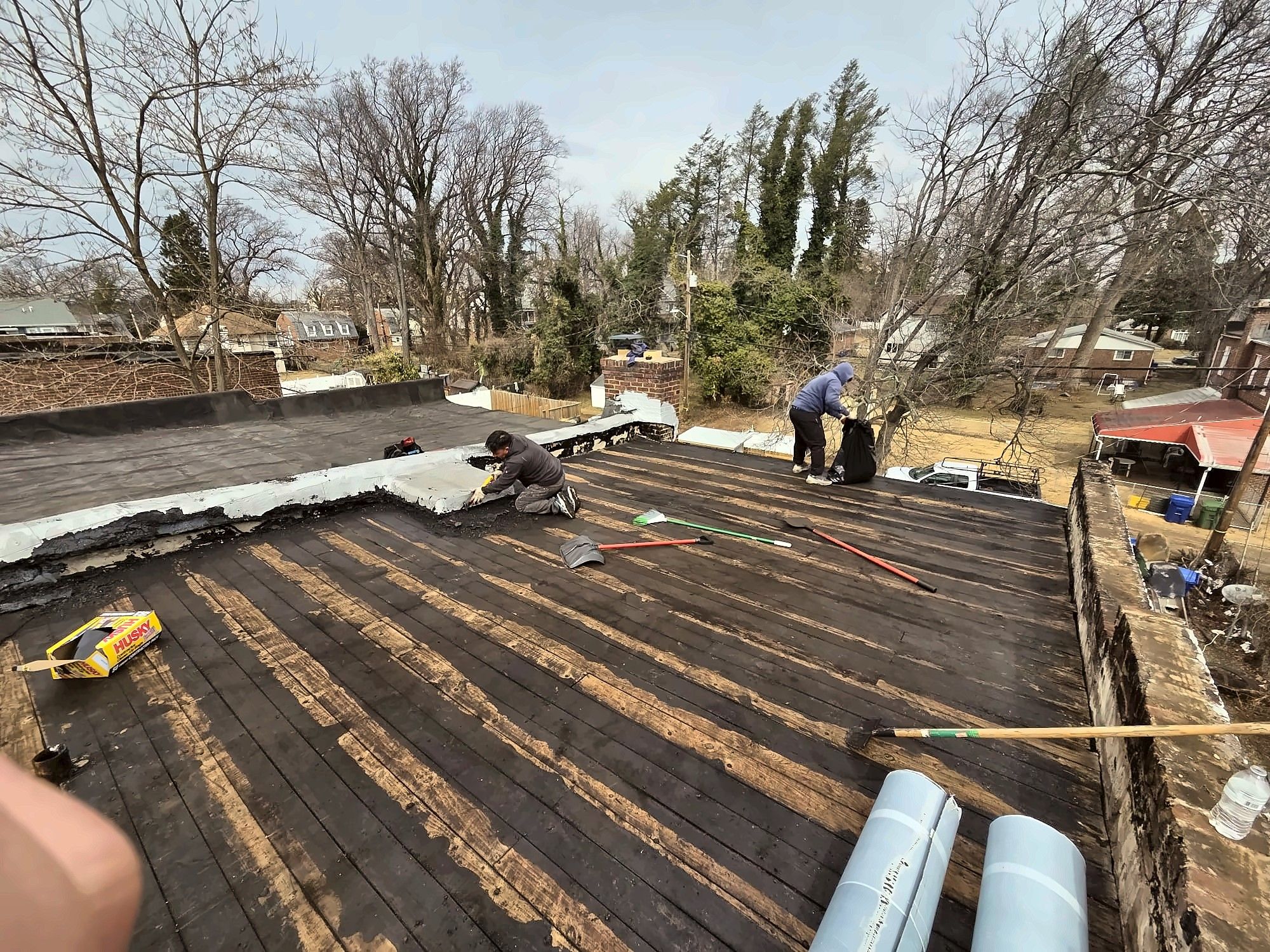 Roofing crew tearing off an old flat roof
