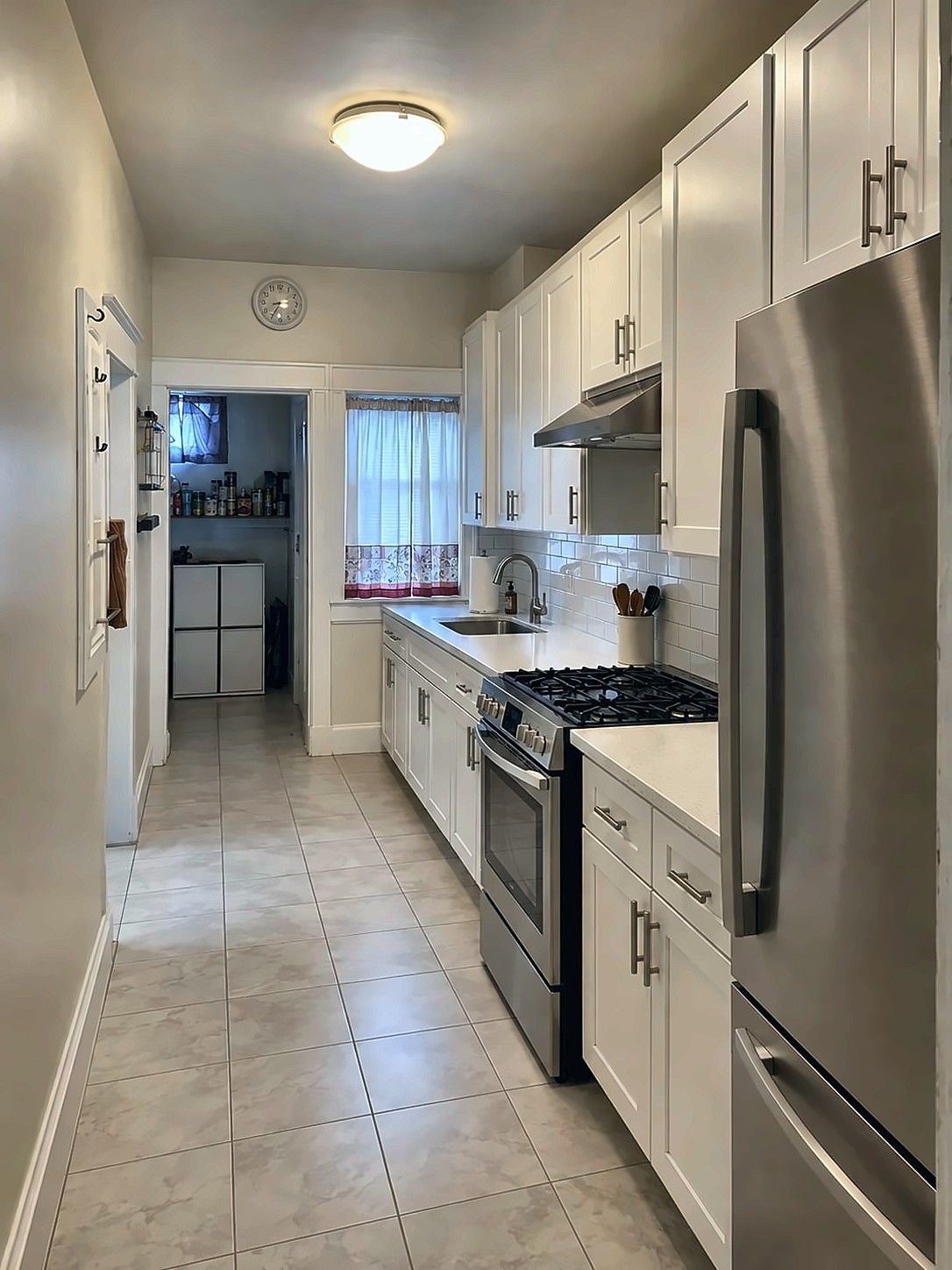 Remodeled galley kitchen with white shaker cabinets and stainless appliances