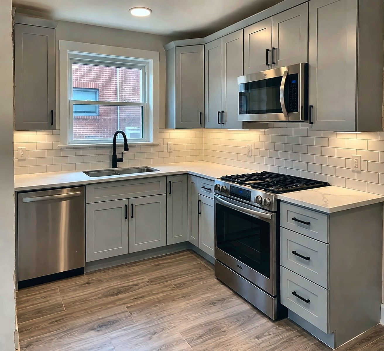 Remodeled kitchen with gray shaker cabinets, quartz counters and subway tile