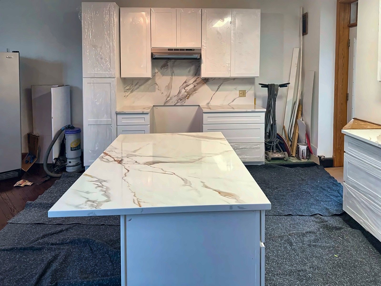 Kitchen installation with white gloss cabinets and marble-look island