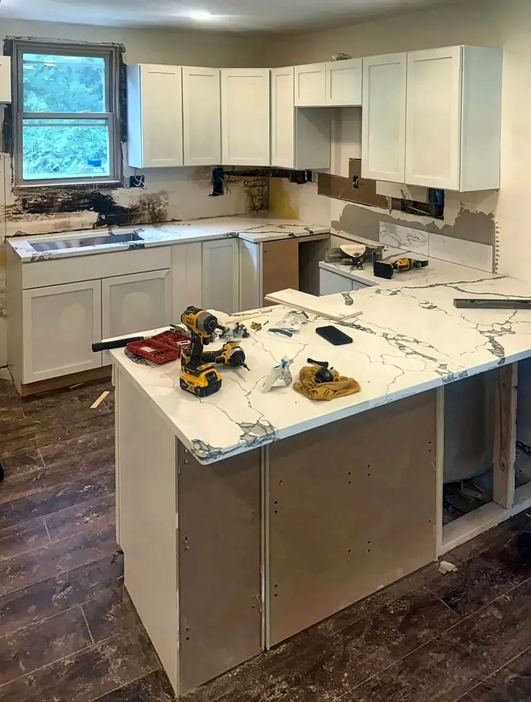 White shaker kitchen with a new marble-look quartz peninsula during installation
