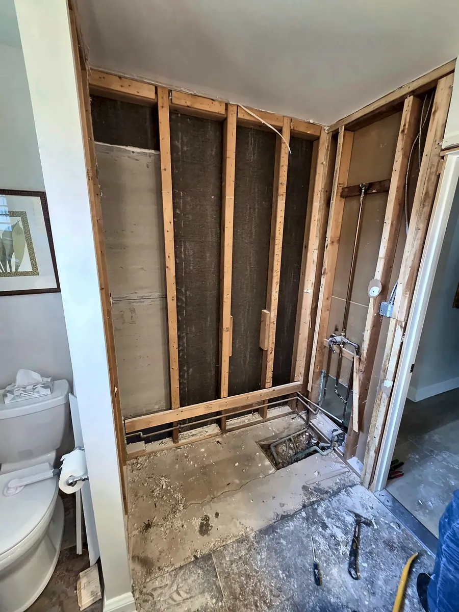 Before: Wide view of a bathroom gutted to the studs