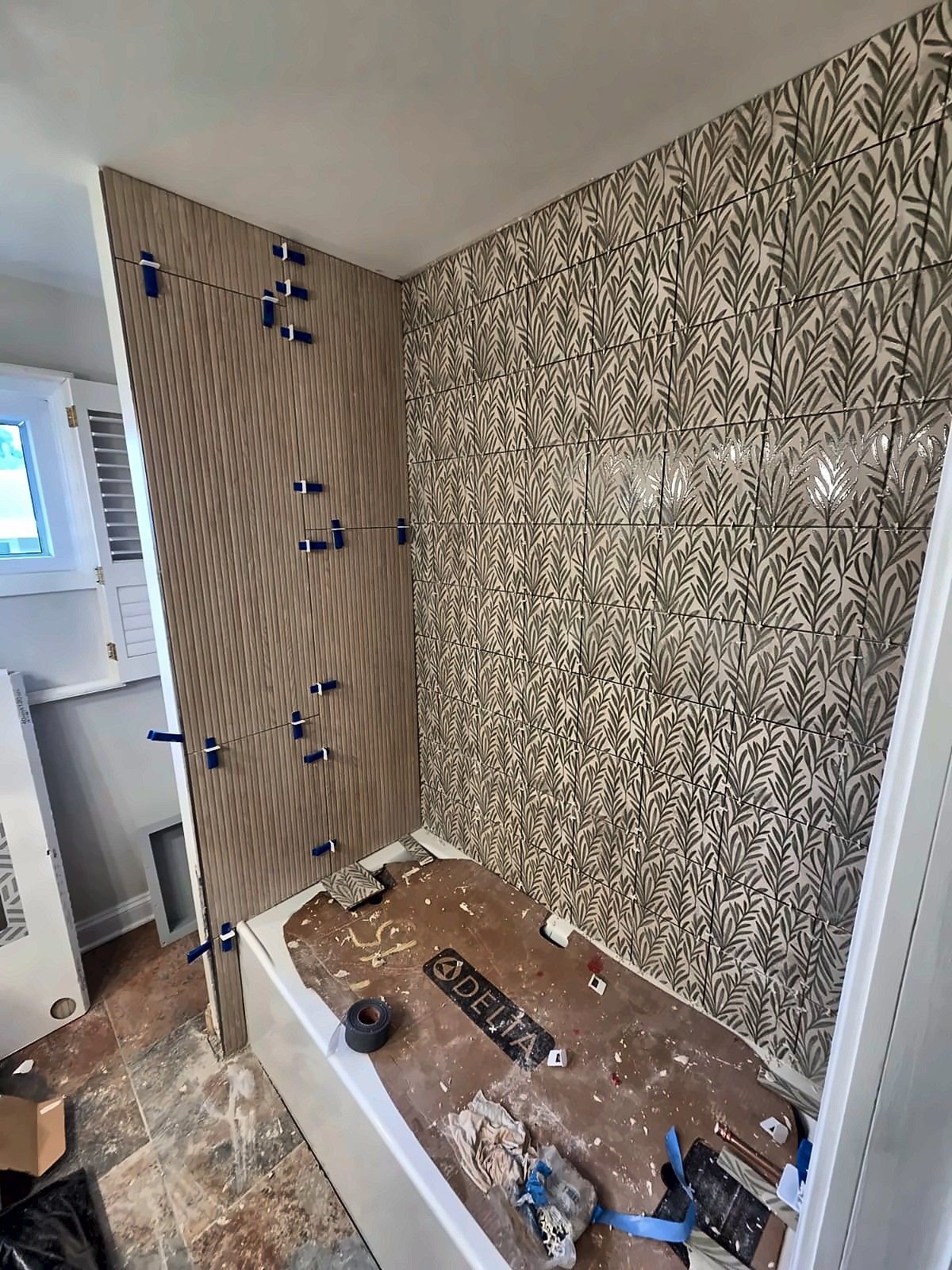 Leaf-pattern tile being installed around a new tub