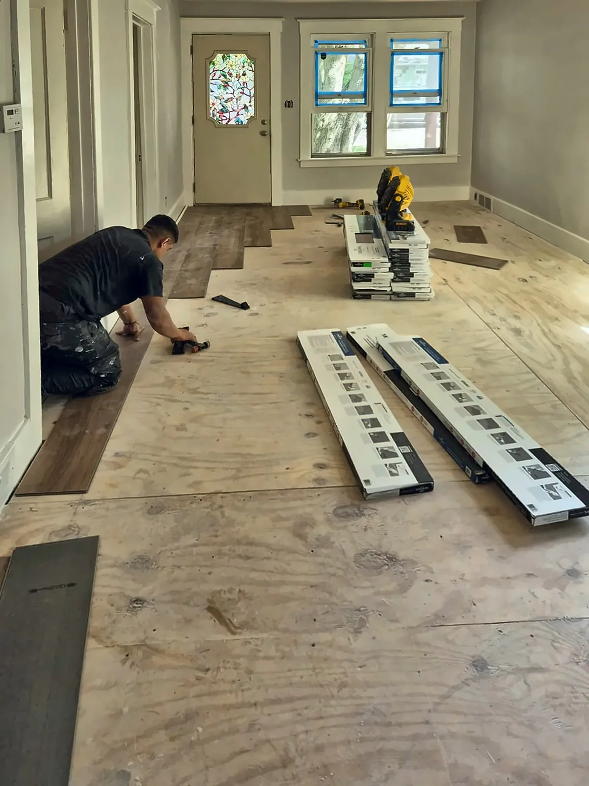 Installer laying vinyl plank over new plywood subfloor