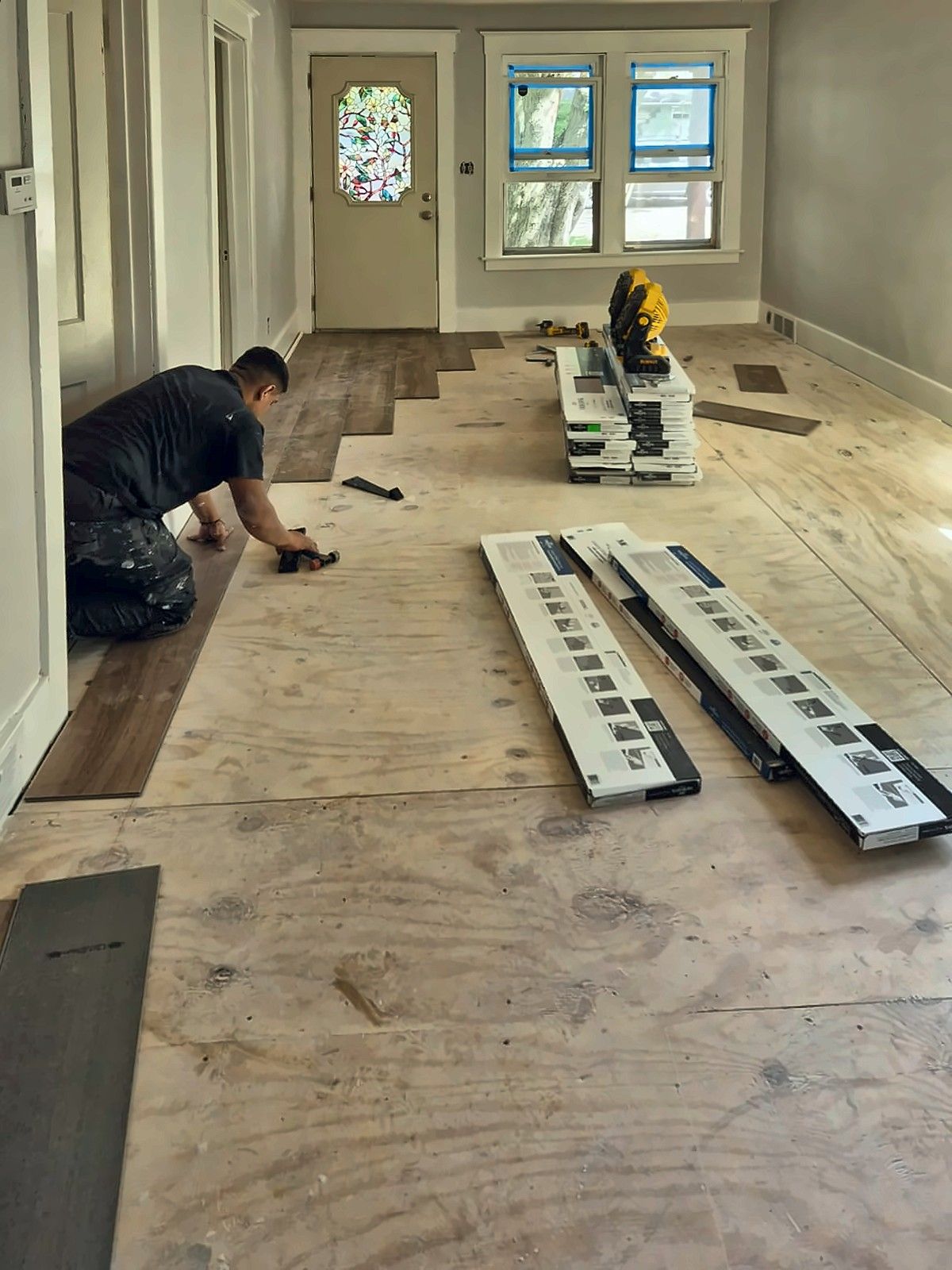 Installer laying vinyl plank over new plywood subfloor