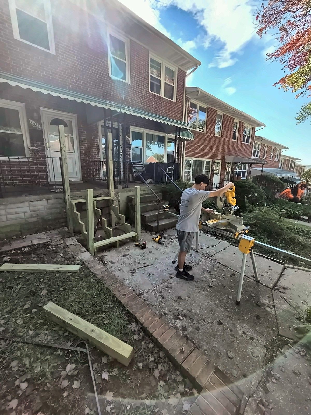 Crew working on new front steps along a row of brick rowhouses