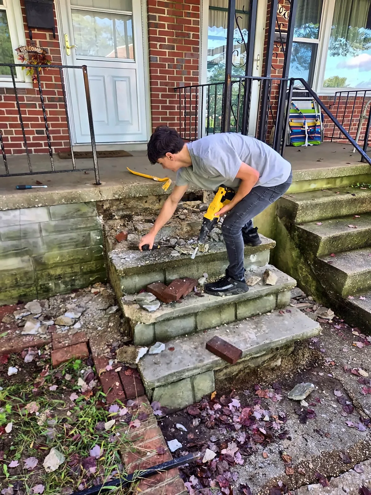 Crew demolishing crumbling concrete front steps at a rowhouse