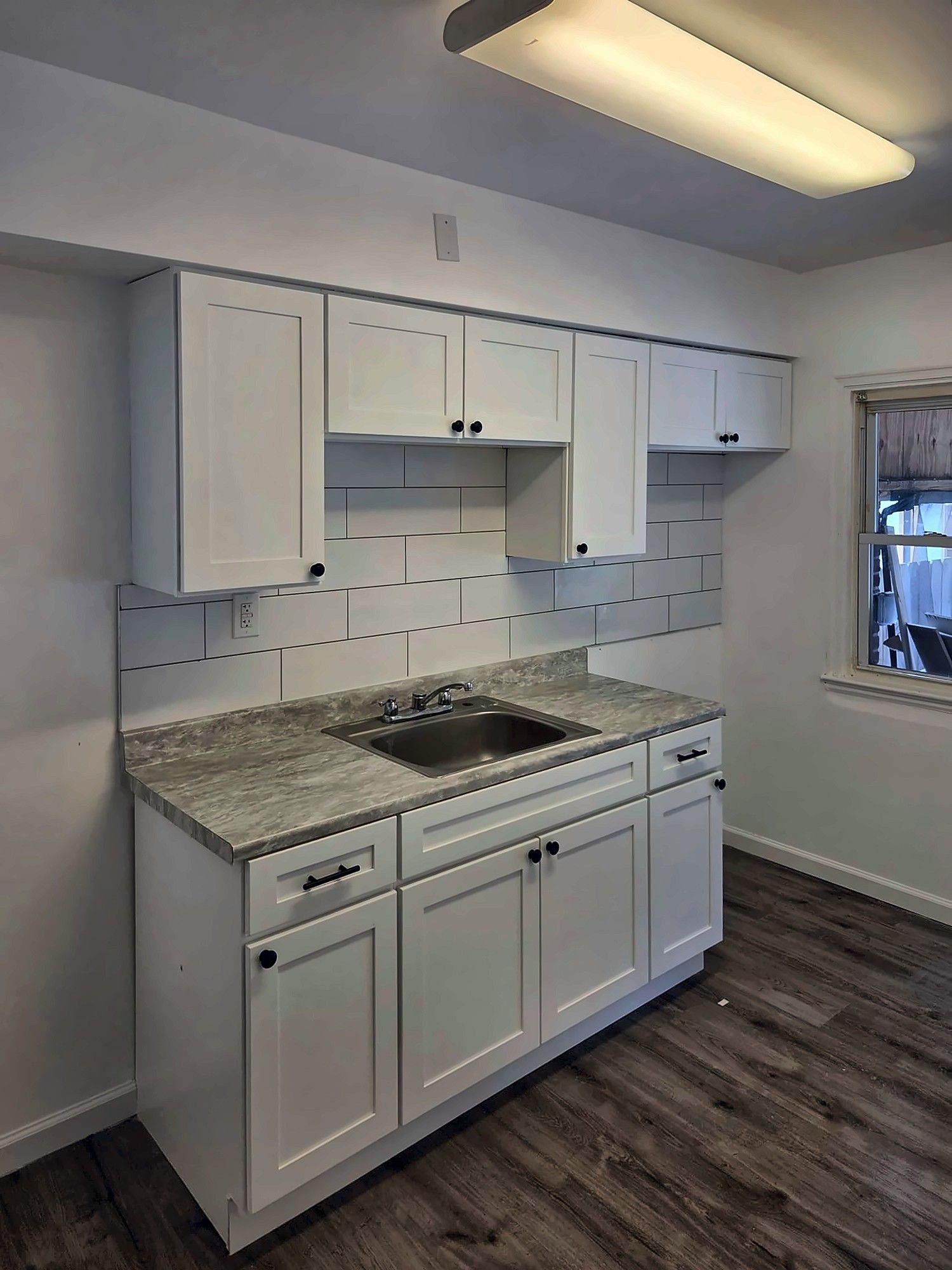 Small remodeled kitchen with white cabinets and subway tile