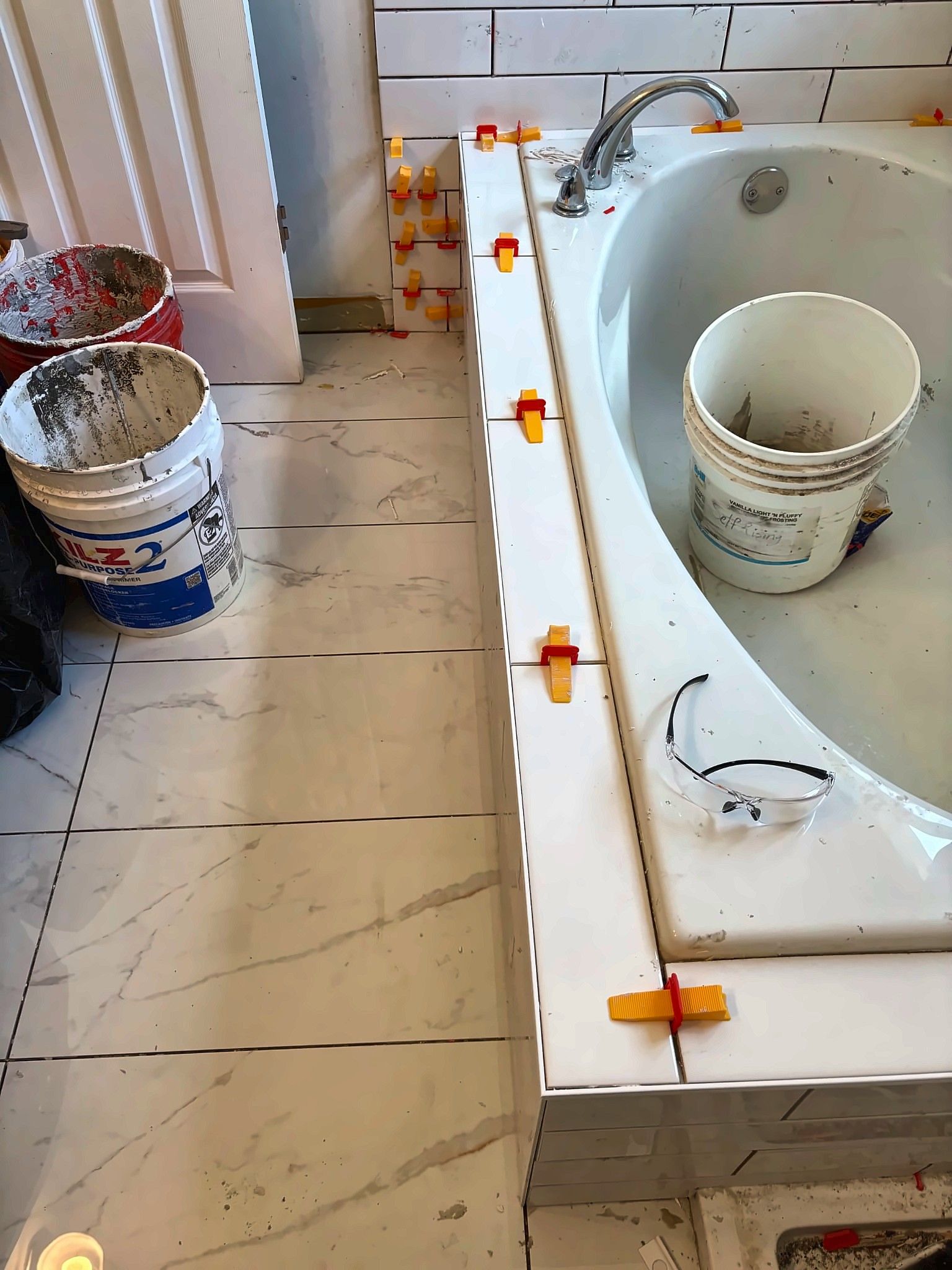 Large-format tile being installed around a soaking tub