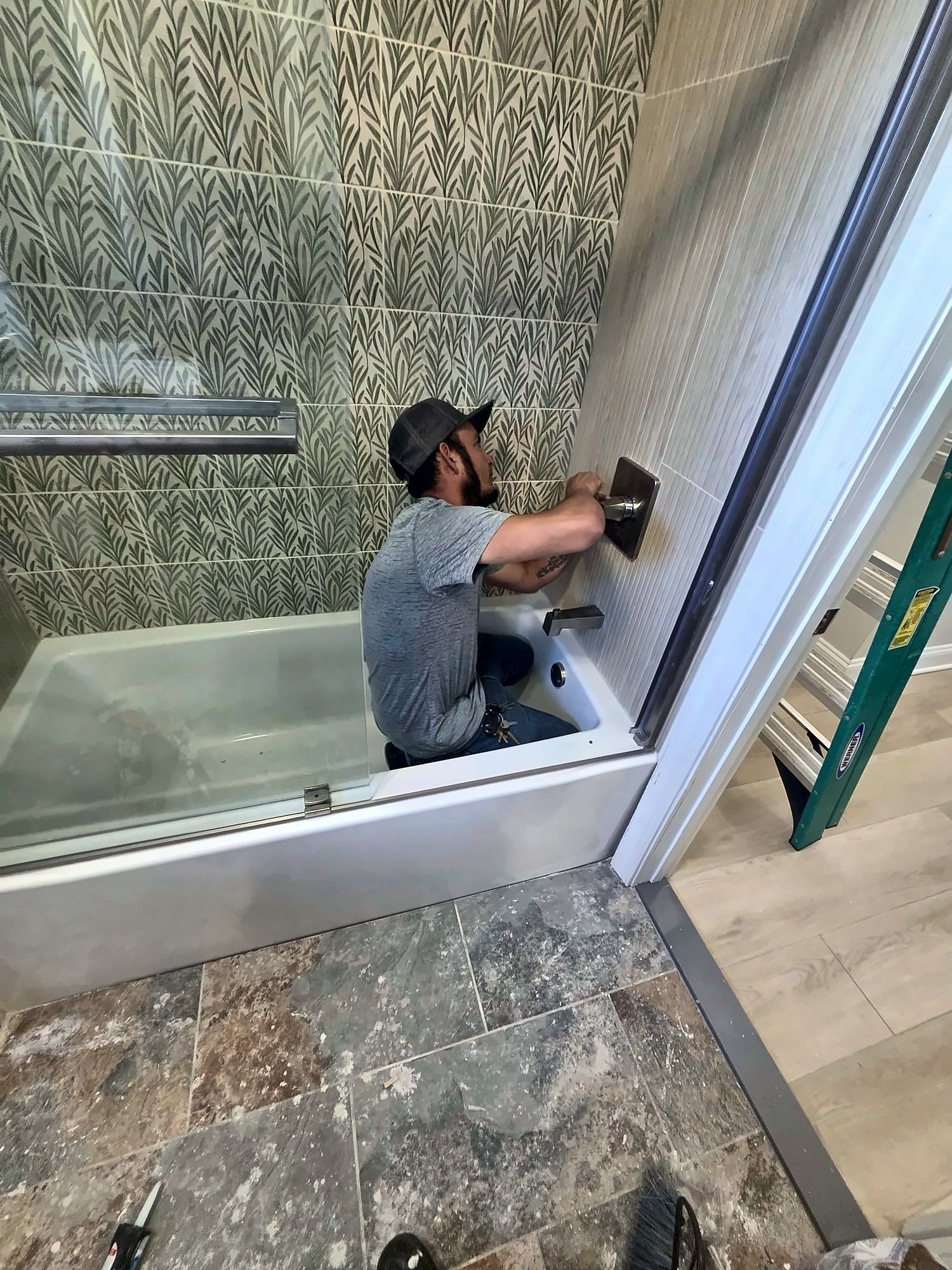 Tile installer setting leaf-pattern tile around a bathtub
