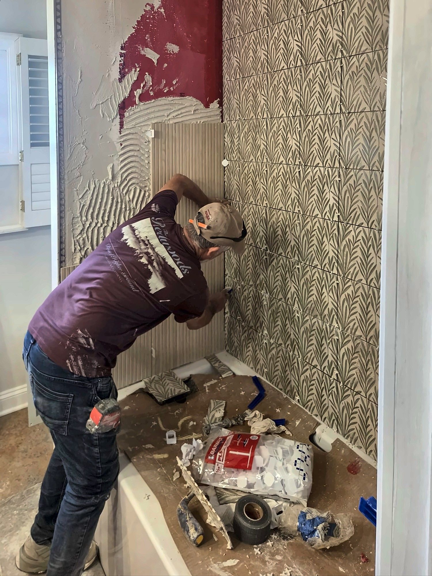 Installer setting tile over red waterproofing membrane