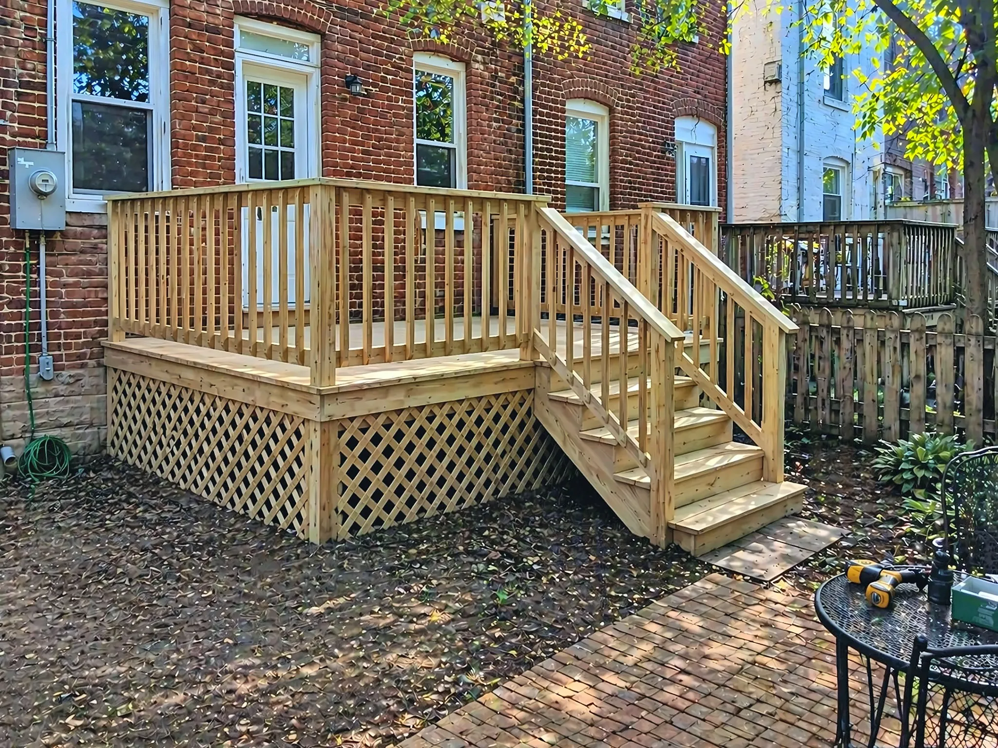New wood deck with stairs behind a brick rowhouse